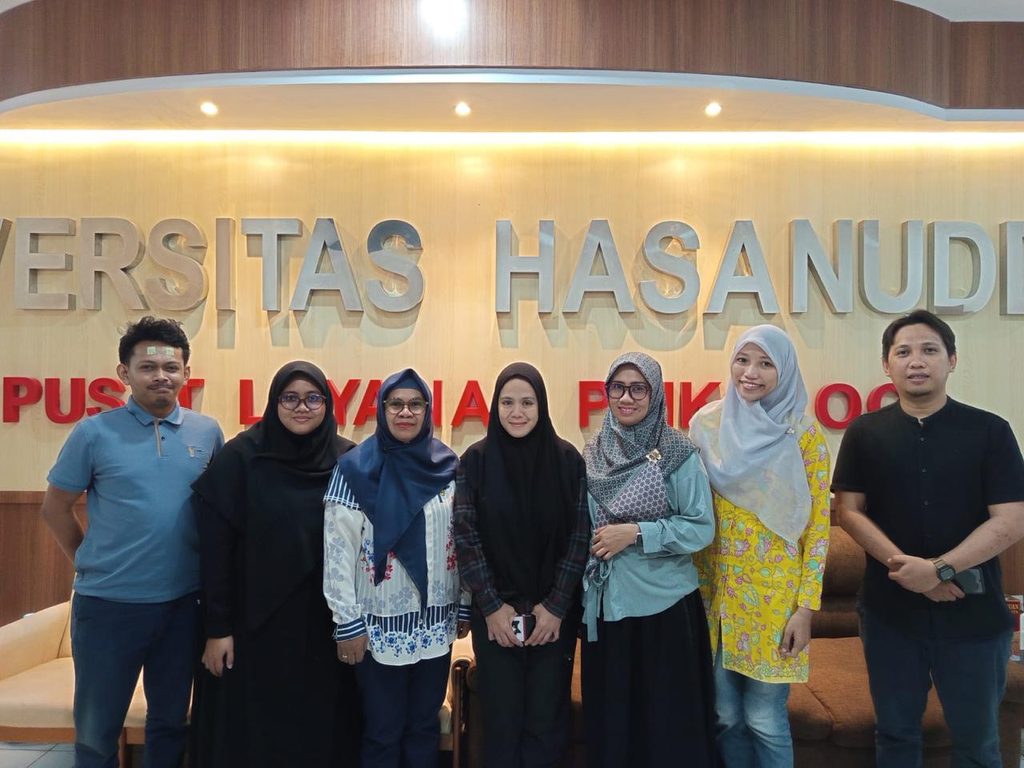 Seven people pose before Universitas Hasanuddin sign