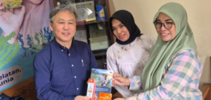 Three adults holding a booklet indoors