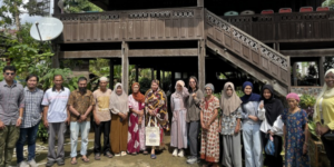 Group standing before wooden stilt house