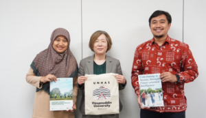 Three people holding university materials and publications