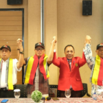 Group of men raising joined hands indoors