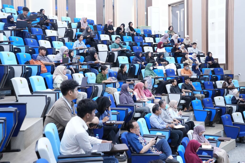 Mahasiswa duduk di ruang kuliah bertingkat