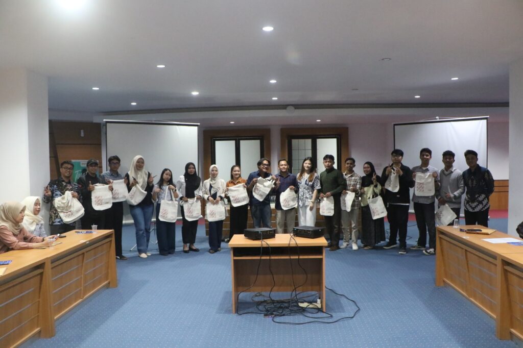 Sekelompok mahasiswa memegang tas tote di ruang rapat