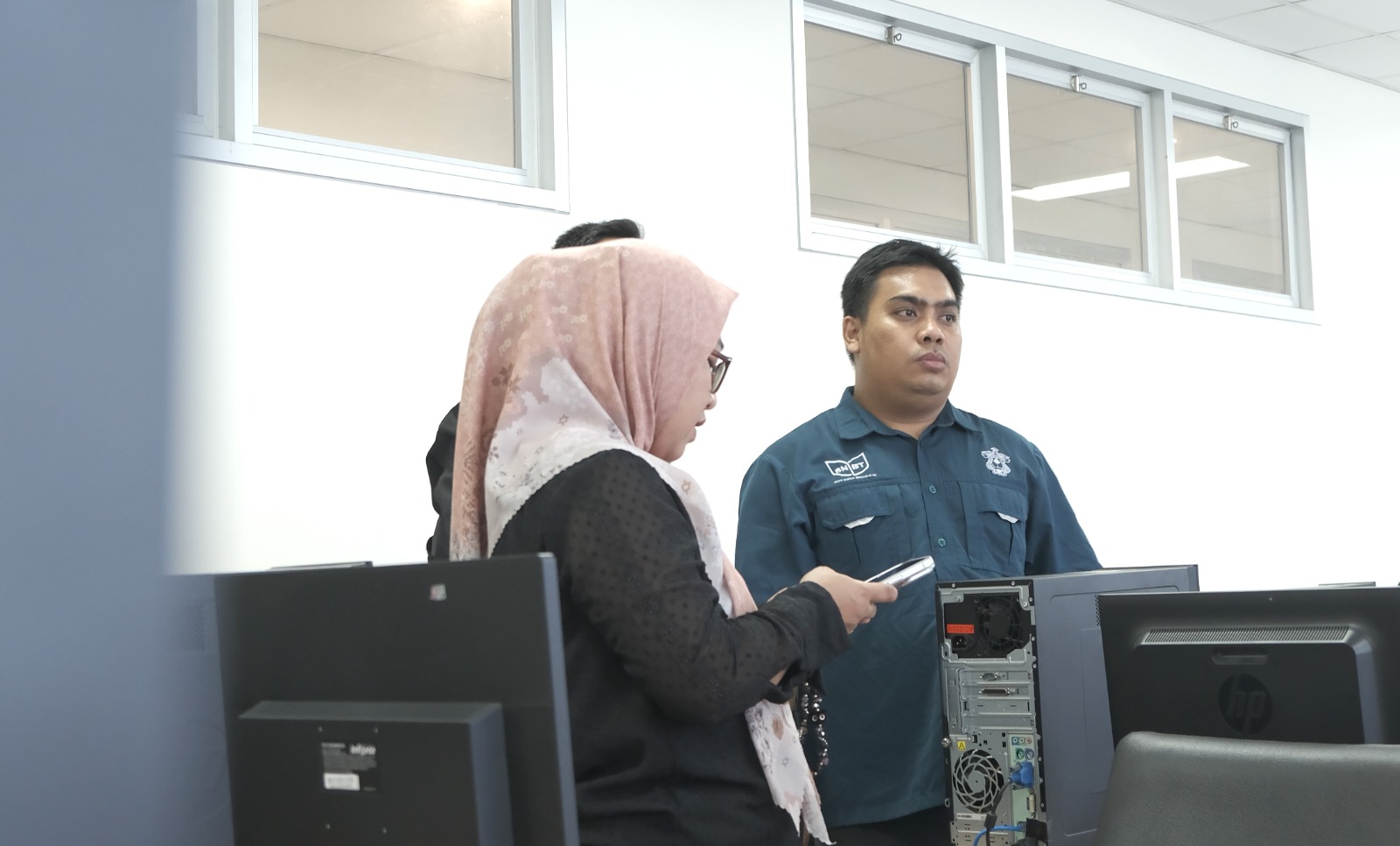 Dua orang berdiskusi di ruang komputer