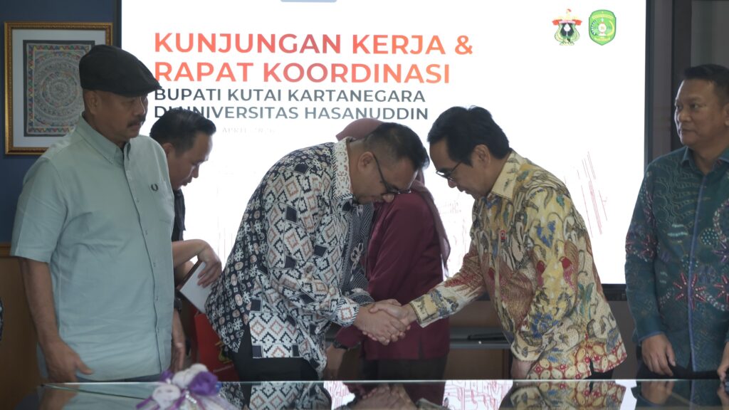 Pejabat berjabat tangan dalam rapat koordinasi resmi
