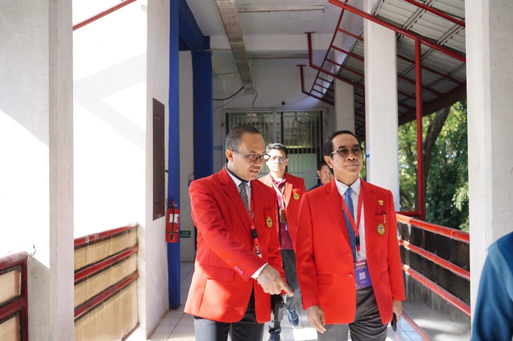 Tiga pria berjas merah berjalan di koridor