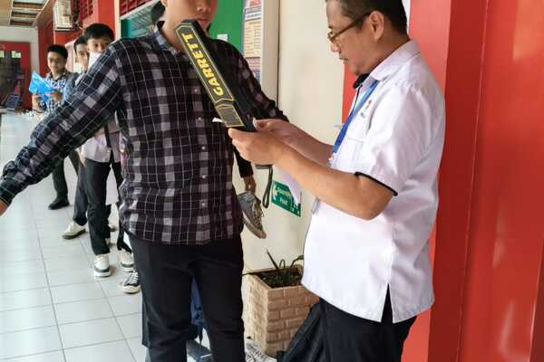 Pemeriksaan siswa dengan detektor logam di sekolah