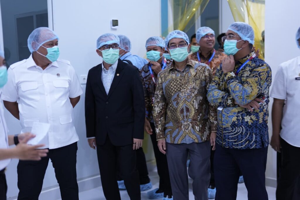 Pejabat bermasker meninjau fasilitas dengan pakaian formal