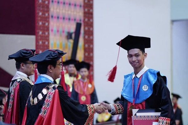 Mahasiswa wisuda berjabat tangan dengan rektor