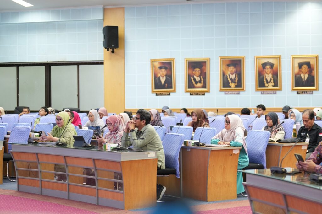Peserta rapat duduk di ruang pertemuan resmi