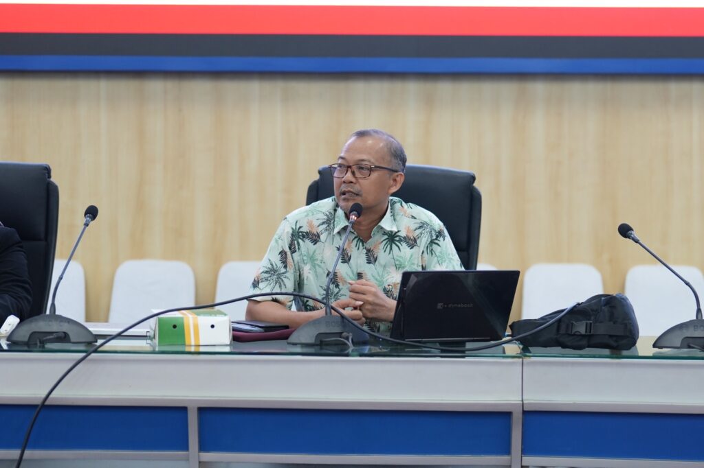Pria berbicara dalam rapat dengan mikrofon dan laptop