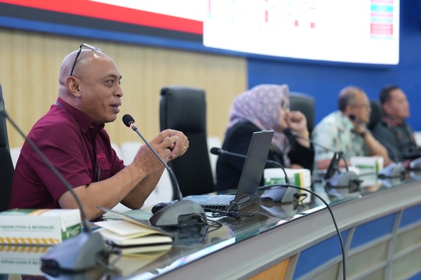 Pria berbicara di rapat dengan mikrofon dan laptop