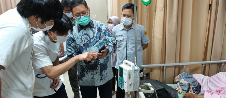 Medical staff reviewing phone beside hospital patient