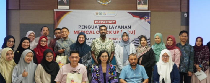 Workshop participants posing before medical checkup banner