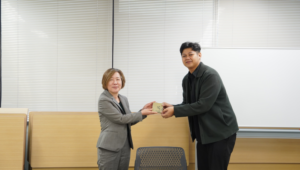 Two professionals exchanging a small gift in office