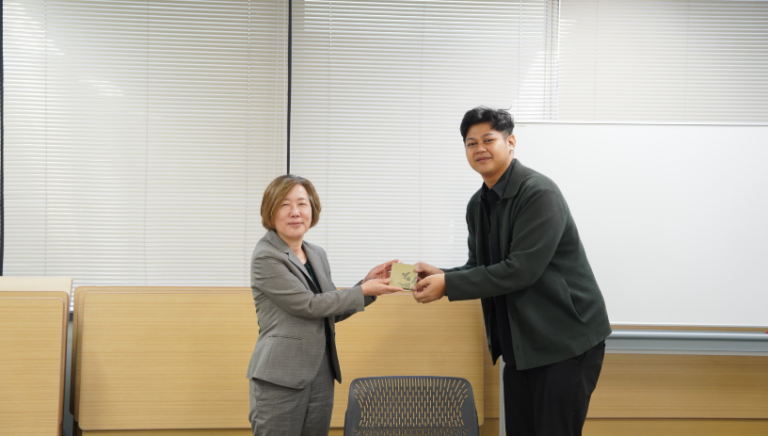Two professionals exchanging a small gift in office