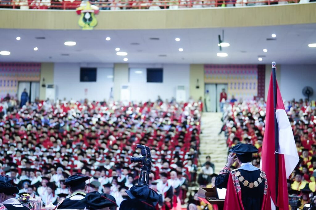 Upacara wisuda di aula besar dengan bendera Indonesia