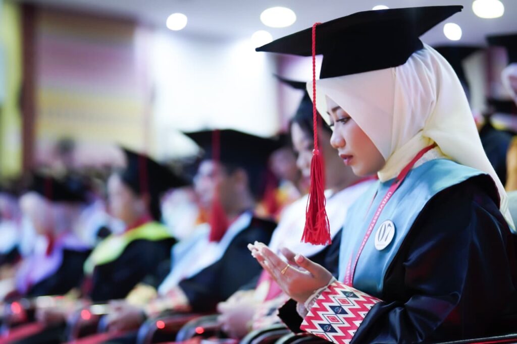 Wisudawati berhijab berdoa saat upacara kelulusan