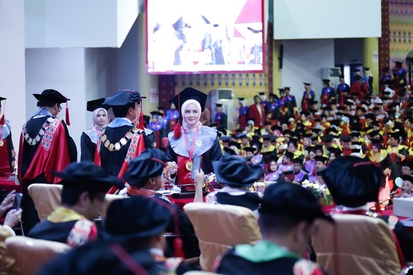 Wisuda universitas dengan rektor dan lulusan berprestasi