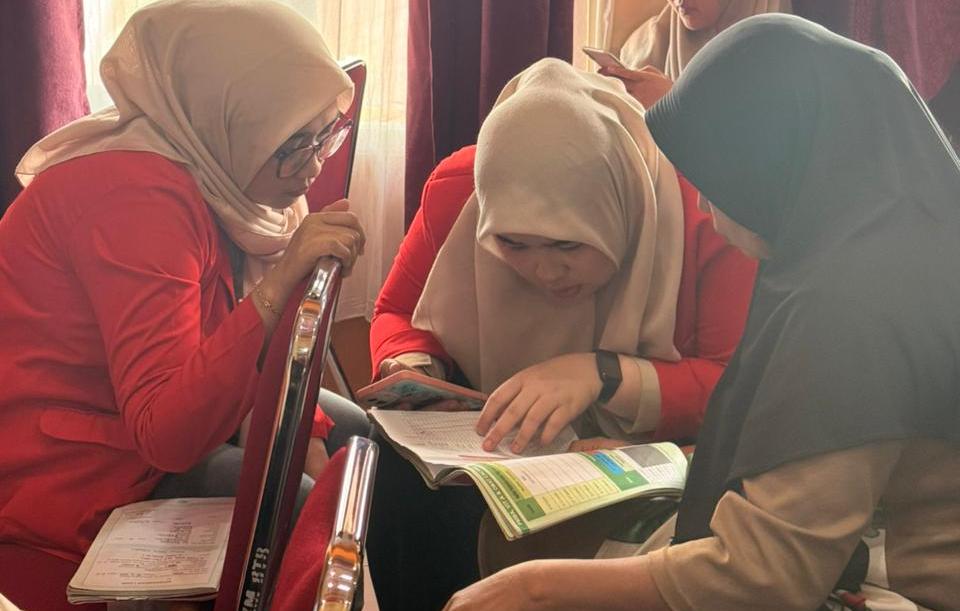 Tiga wanita berhijab belajar bersama membaca buku