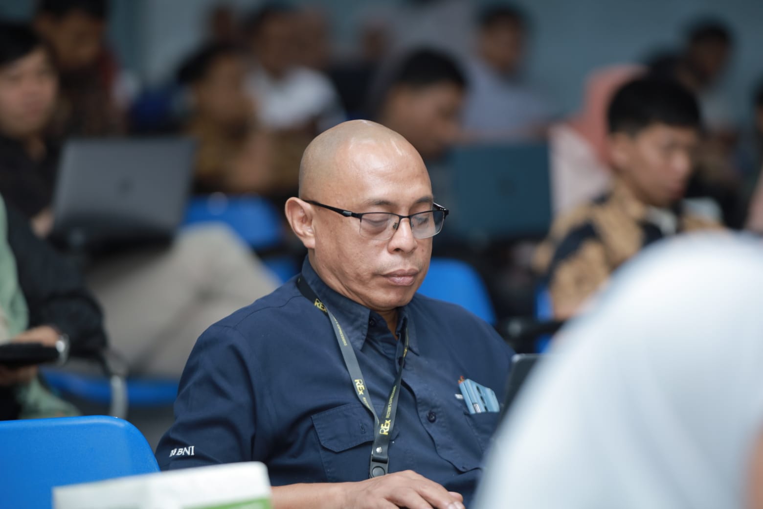 Pria berkacamata fokus menggunakan laptop di seminar