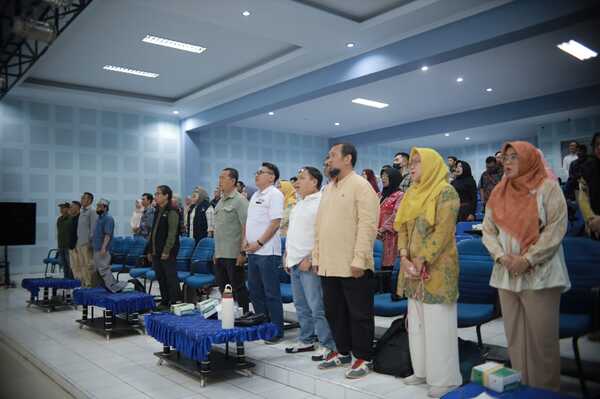 Peserta berdiri di aula menghadiri acara resmi