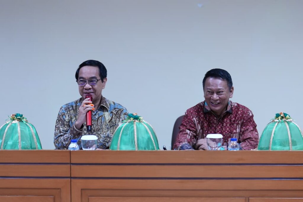 Dua pria berbaju batik di meja rapat
