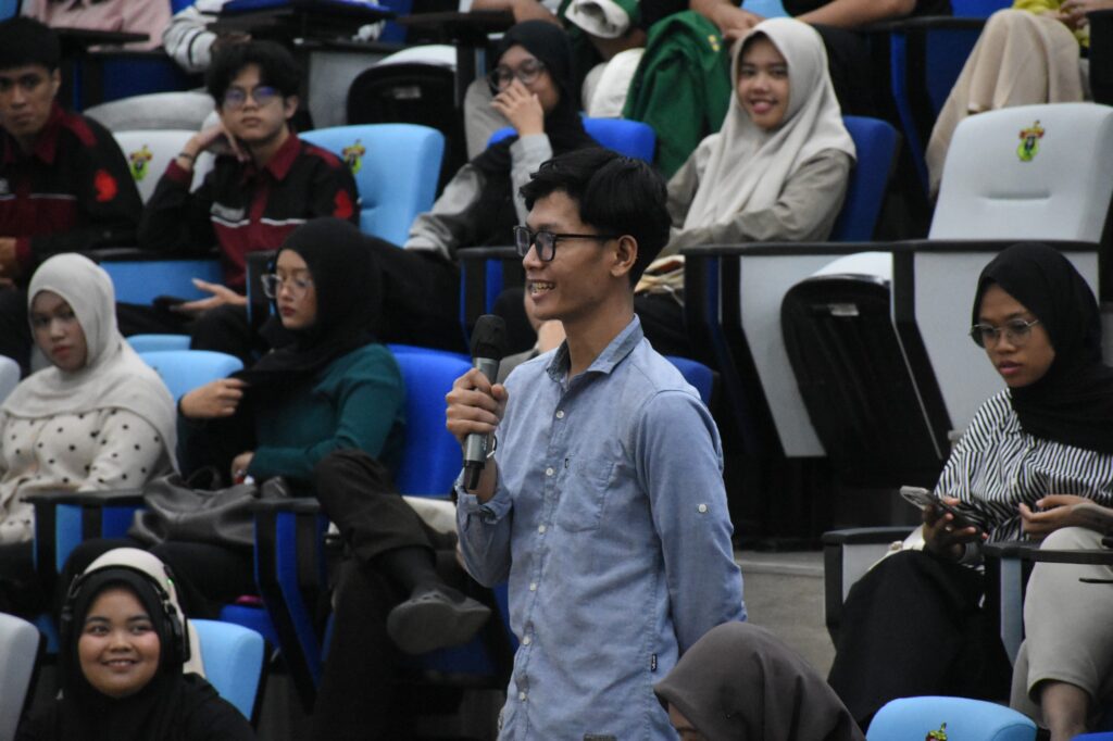 Mahasiswa berbicara dengan mikrofon di ruang kuliah