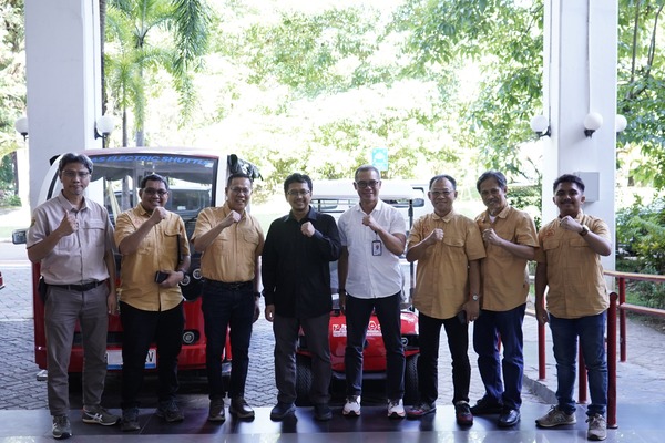 Sekelompok pria berpose di depan shuttle merah