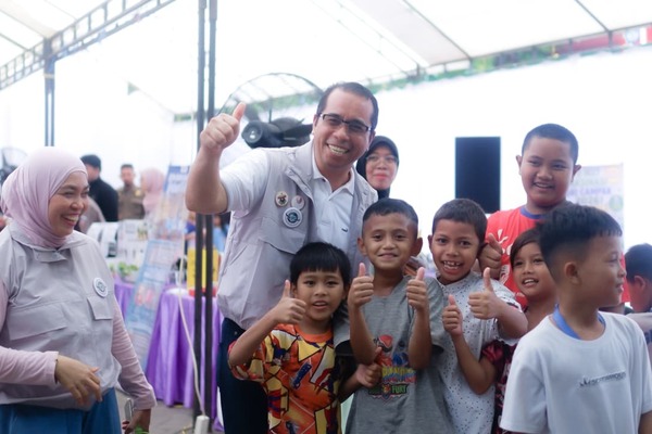 Pria berseragam berfoto bersama anak-anak tersenyum