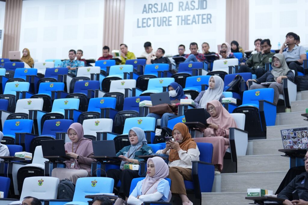 Peserta duduk di ruang kuliah bertingkat dengan laptop