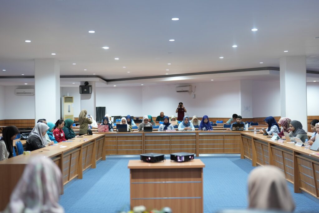 Mahasiswa mengikuti kelas dengan laptop di ruang rapat