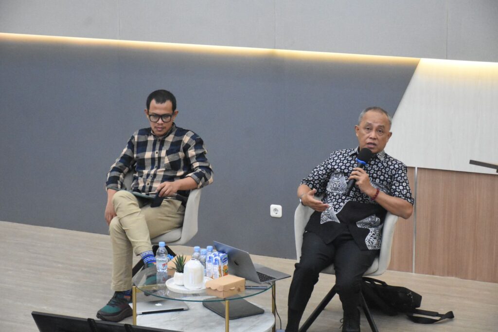 Dua pria berbicara dalam diskusi panel indoor