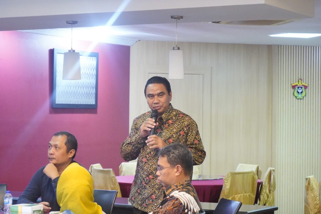 Pria berbaju batik berbicara dalam rapat
