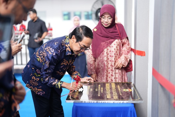 Man signing commemorative plaque at ceremony