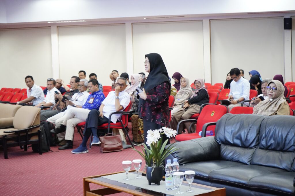 Perempuan berhijab berbicara di ruang seminar