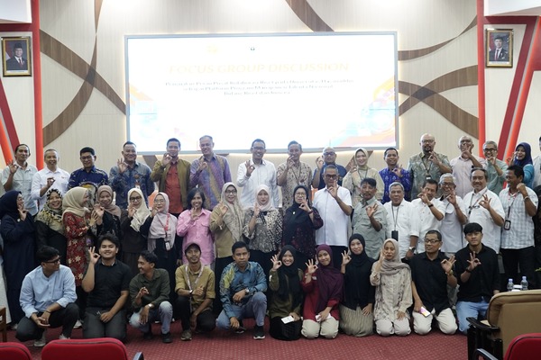 Kelompok orang berfoto di auditorium dengan gesture hati