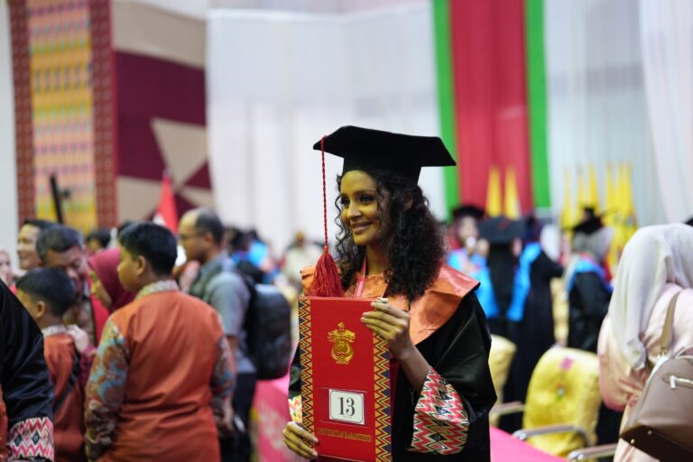 Graduate holding red diploma at ceremony