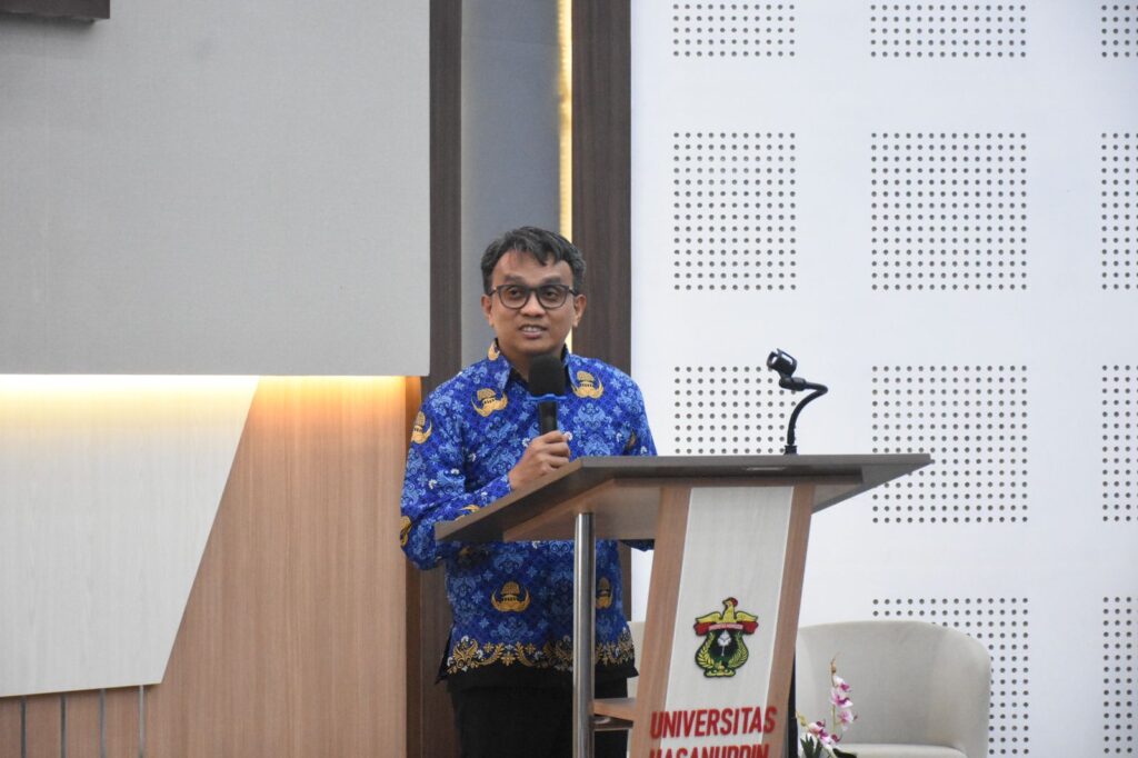 Pria berbatik berbicara di podium universitas