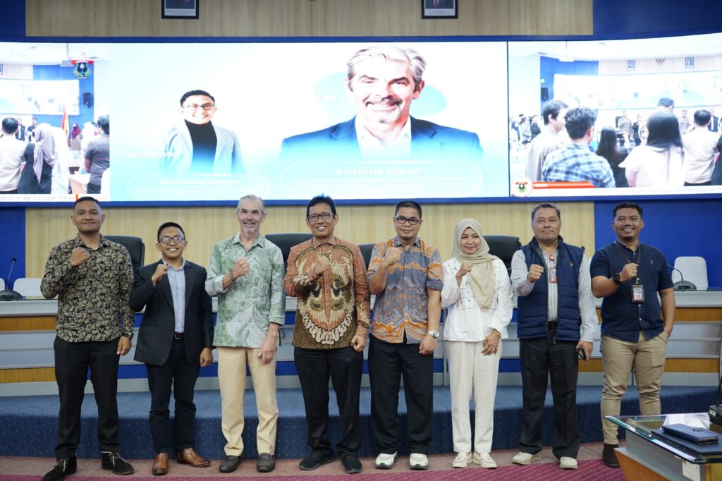 Kelompok peserta berpose di depan layar konferensi