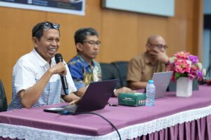 Pembicara memegang mikrofon dalam seminar
