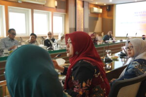 Woman in red hijab speaking at conference table