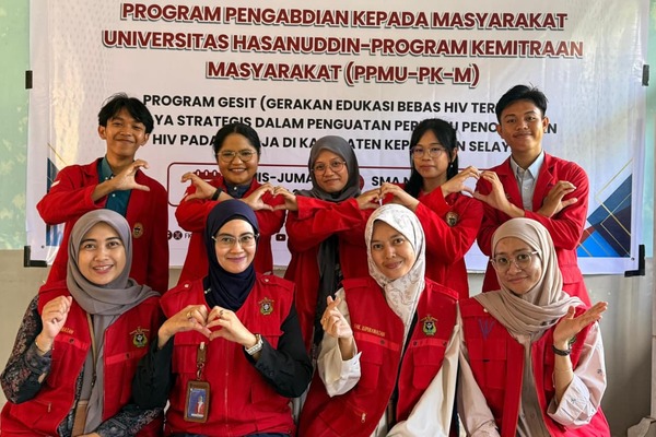 Mahasiswa berjaket merah berpose di depan banner