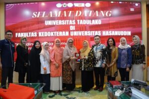 Rombongan universitas berfoto di depan layar sambutan
