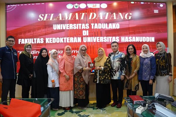 Rombongan universitas berfoto di depan layar sambutan