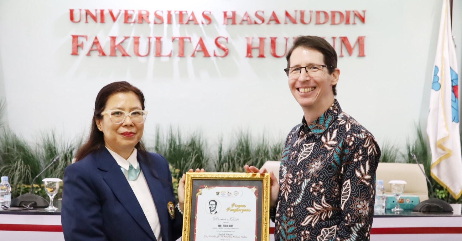 Two people holding framed award at university event