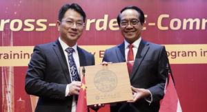 Two officials exchange plaque at business event