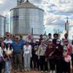 Group posing in front of large farm silos