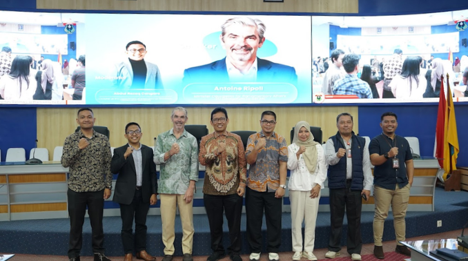 Group posing at conference with large presentation screen