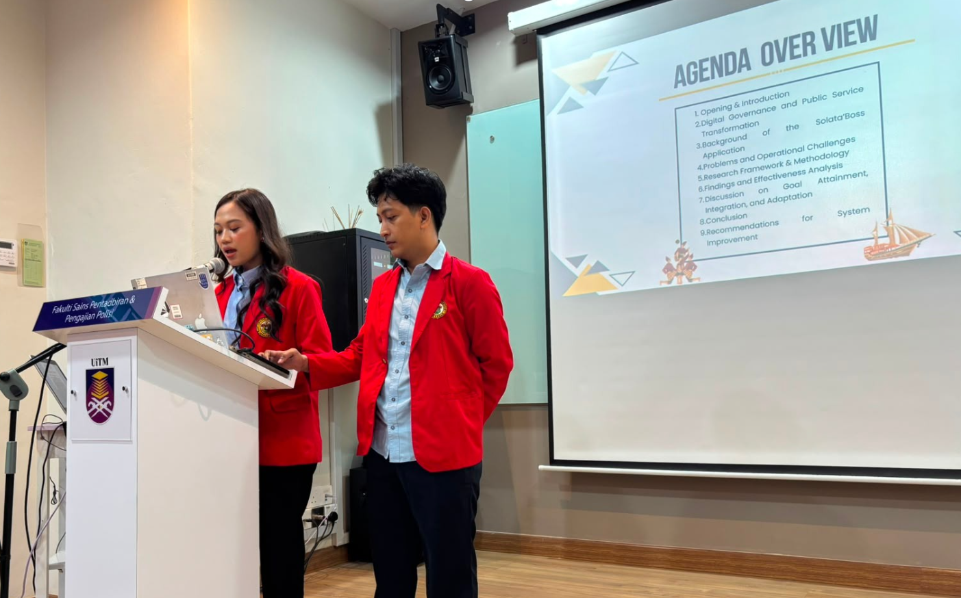 Students presenting at podium with agenda slide